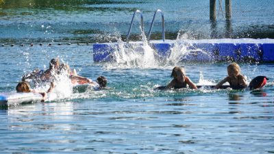 Några barn som plaskar och badar i en sjö.