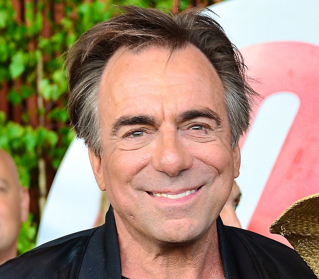 Rikard Wolff ler mot kameran. Han har svart hår som är grått vid tinningarna och har ganska mycket rynkor. Han har en svart skinnjacka på sig,