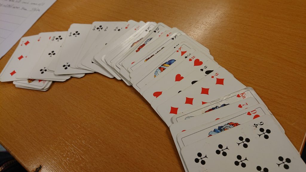 En kortlek ligger uppvända i en halvcirkel på ett bord