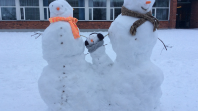 Tre snögubbar utanför en skola