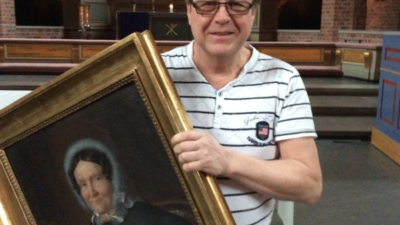 Man i en kyrka med en tavla i handen