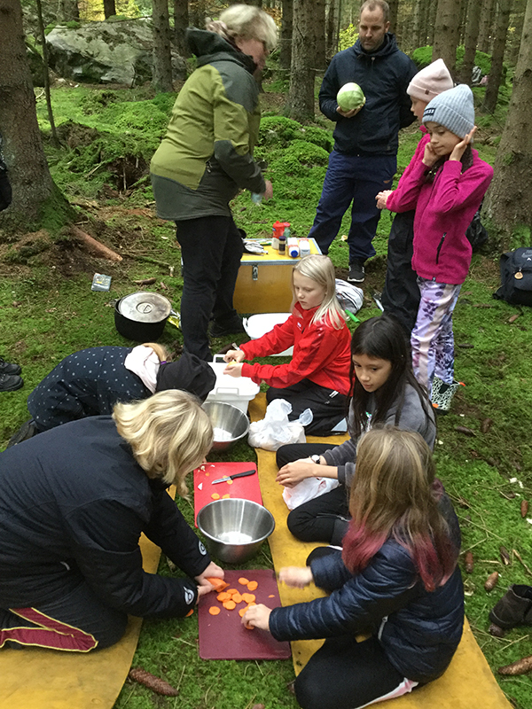 Eleverna sitter i skogen och förbereder sin mat.