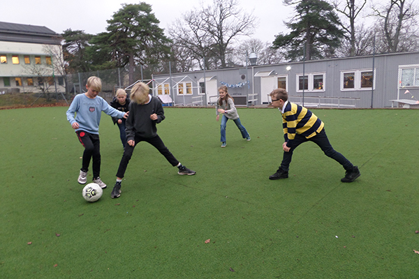 Foto på elever som spelar fotboll på skolans fotbollsplan.