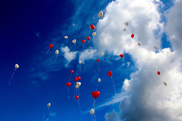 Hjärtformade ballonger som flyger upp bland molnen.