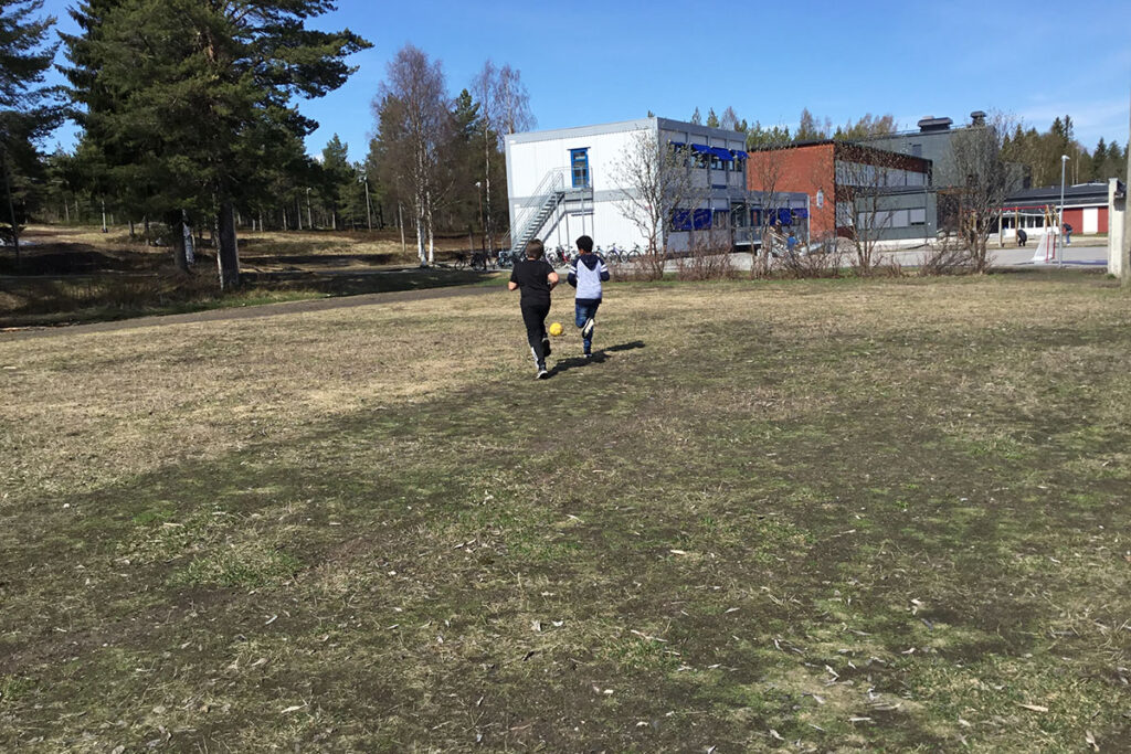 Två elever som springer på fotbollsplanen.